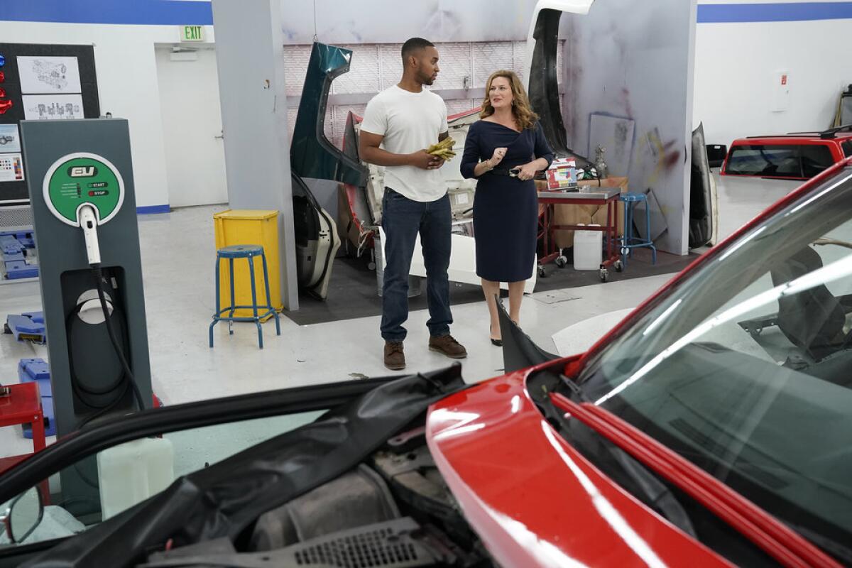 A man and a woman standing on an auto body shop floor