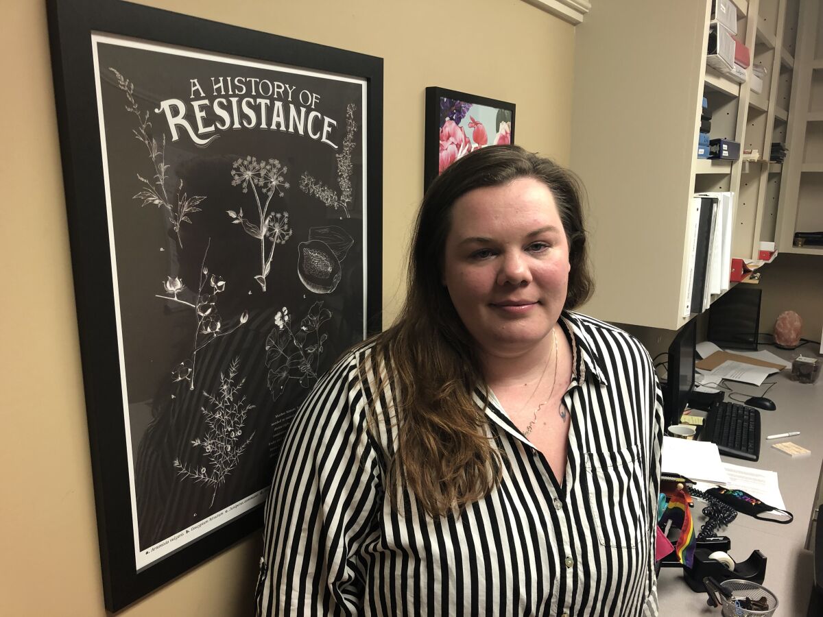 Ashley Brink with a wall poster that reads "A History of Resistance"