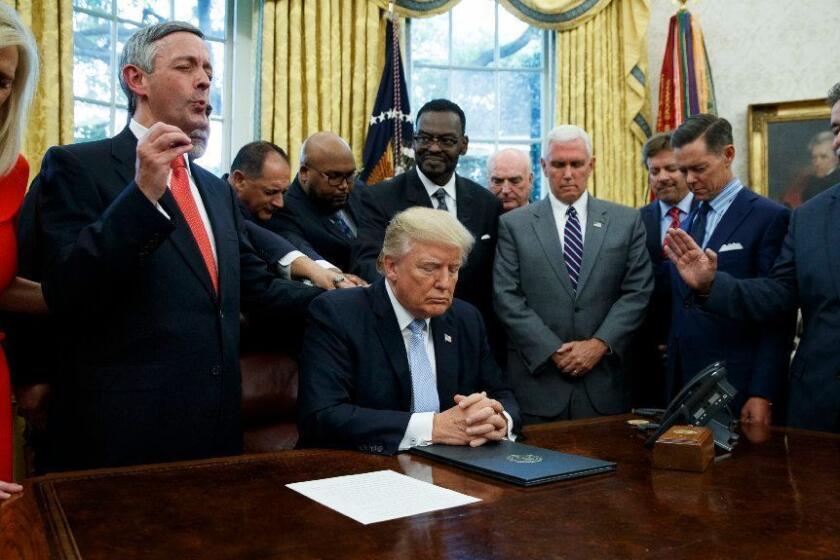 FILE - In this Sept. 1, 2017 file photo, religious leaders pray with President Donald Trump after he signed a proclamation for a national day of prayer to occur on Sunday, Sept. 3, 2017, in the Oval Office of the White House in Washington. Religion's role in politics and social policies is in the spotlight heading toward the midterm elections, yet relatively few Americans consider it crucial that a candidate be devoutly religious or share their religious beliefs, according to an AP-NORC national poll conducted Aug. 16-20, 2018. (AP Photo/Evan Vucci)