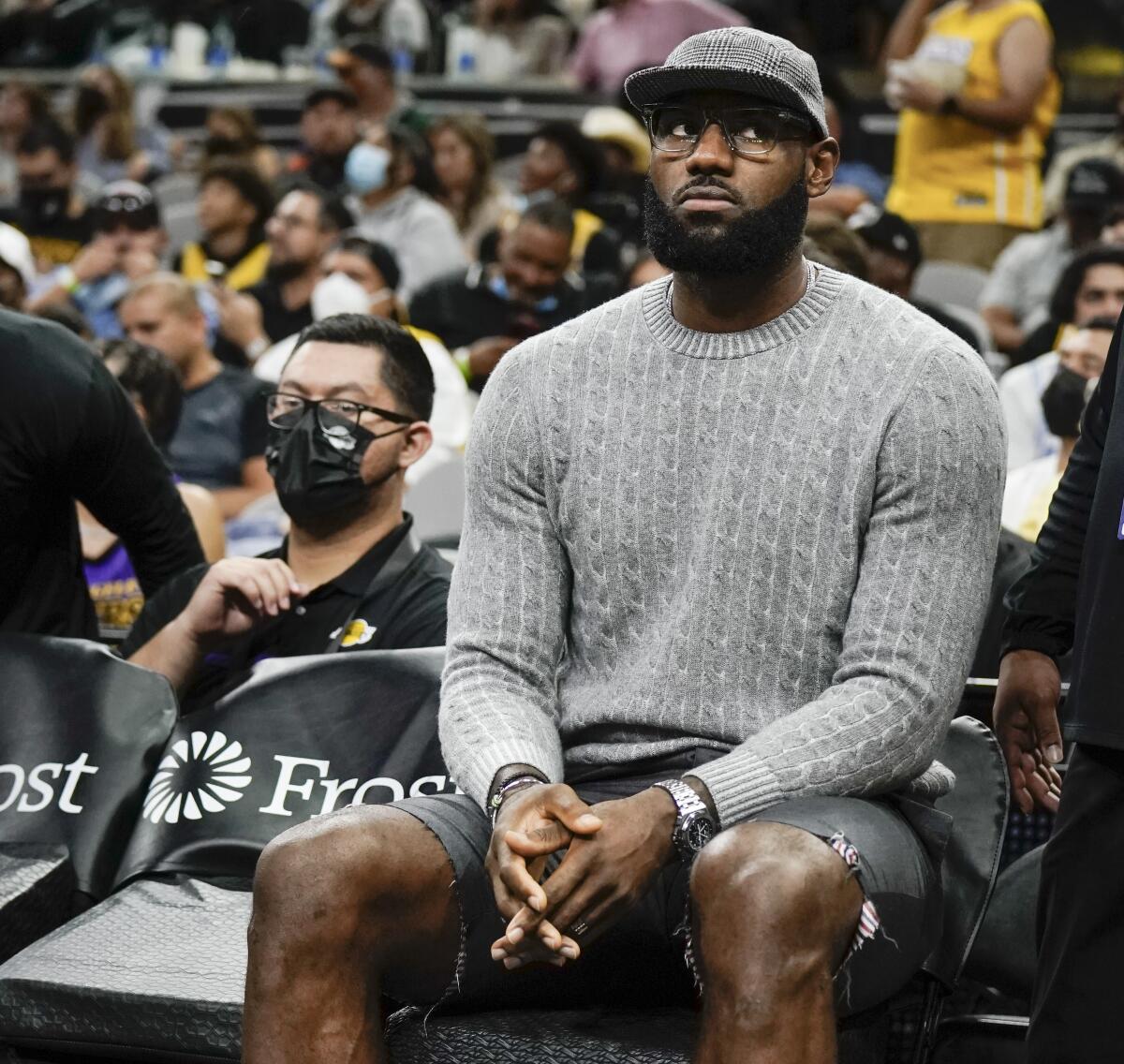 Lakers forward LeBron James sits on the bench in street clothes during a game against the San Antonio Spurs 