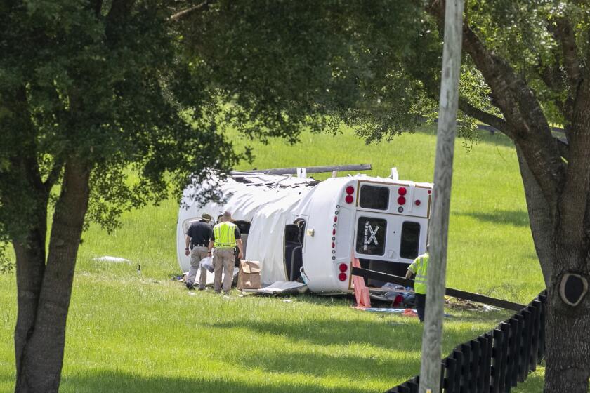 Policía y socorristas inspeccionan un autobús que se volcó tras chocar con una camioneta matando a ocho de 50 jornaleros que iban en el camión, el 14 de mayo de 2024, en Ocala, Florida. (Foto AP/Alan Youngblood)