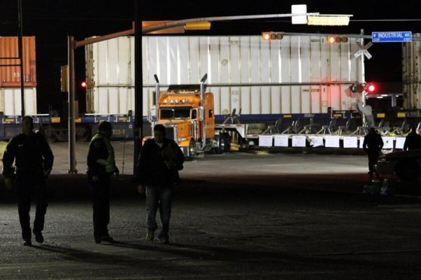 Police officers walk in front of a trailer that was carrying wounded veterans in a parade when it was struck Thursday by a train in Midland, Texas.