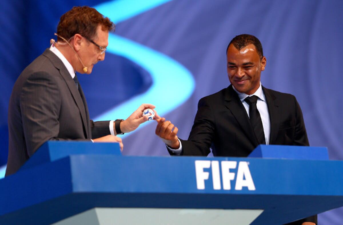 Former Brazilian star Cafu passes a ball with a country's name inside to FIFA Secretary General Jerome Valcke during the preliminary-group draw on Friday.
