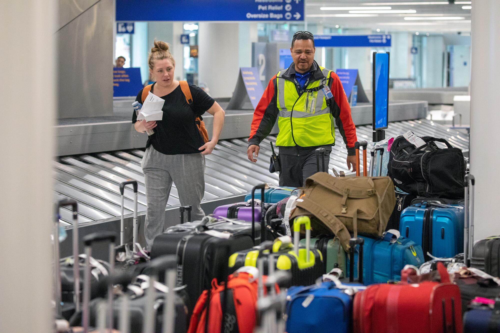 A Southwest Airlines employee, right, helps a woman locate her luggage at an airport.