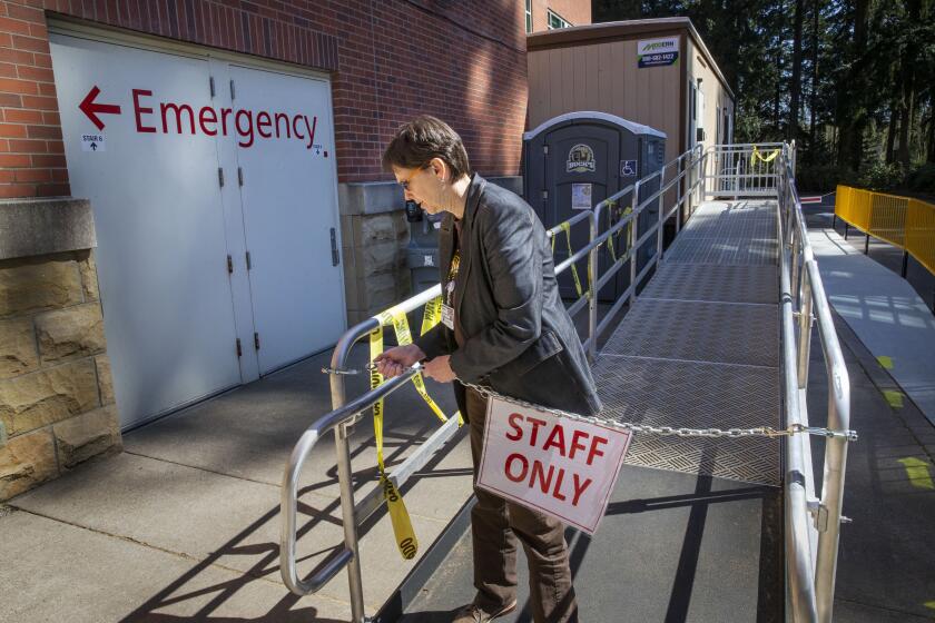 Chief Medical Officer for PeaceHealth Oregon network Dr. Andrea Halliday tours a newly created triage trailer site that has been set up to handle suspected COVID-19 cases at the RiverBend Hospital in Springfield, Oregon Sunday March 22, 2020. (Chris Pietsch/The Register-Guard via AP)