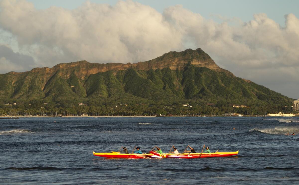 An outrigger canoe paddles past Diamond Head mountain in Honolulu. Hawaii is a popular destination for California lawmakers every November, although they prefer Maui.