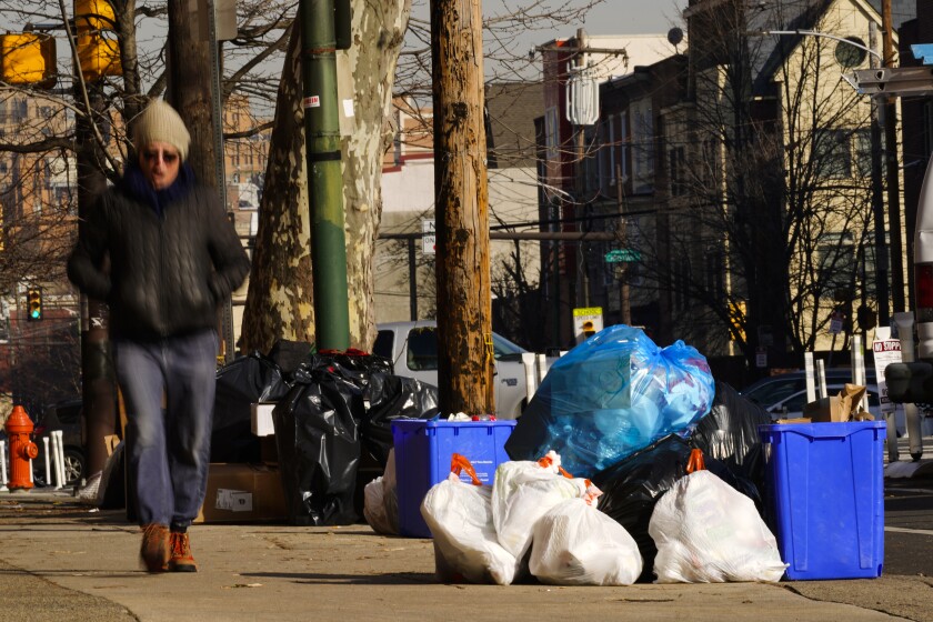 Trash sits out for collection in Philadelphia, Thursday, Jan. 13, 2022. The omicron variant is sickening so many sanitation workers around the U.S. that waste collection in Philadelphia and other cities has been delayed or suspended. (AP Photo/Matt Rourke)