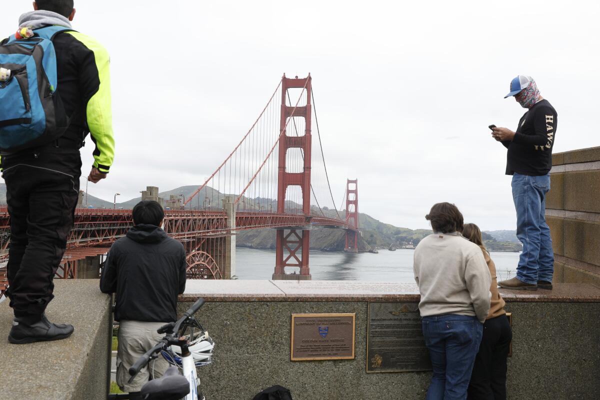 Pedestrians and bicyclists wait outside the pedestrian gate on the south side of the 