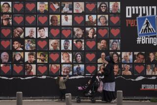 FILE - A woman and her children walk past a wall with photographs of hostages who were kidnapped during the Oct. 7 Hamas cross-border attack in Israel in Jerusalem, Israel, Monday, Feb. 26, 2024. (AP Photo/Leo Correa, File)