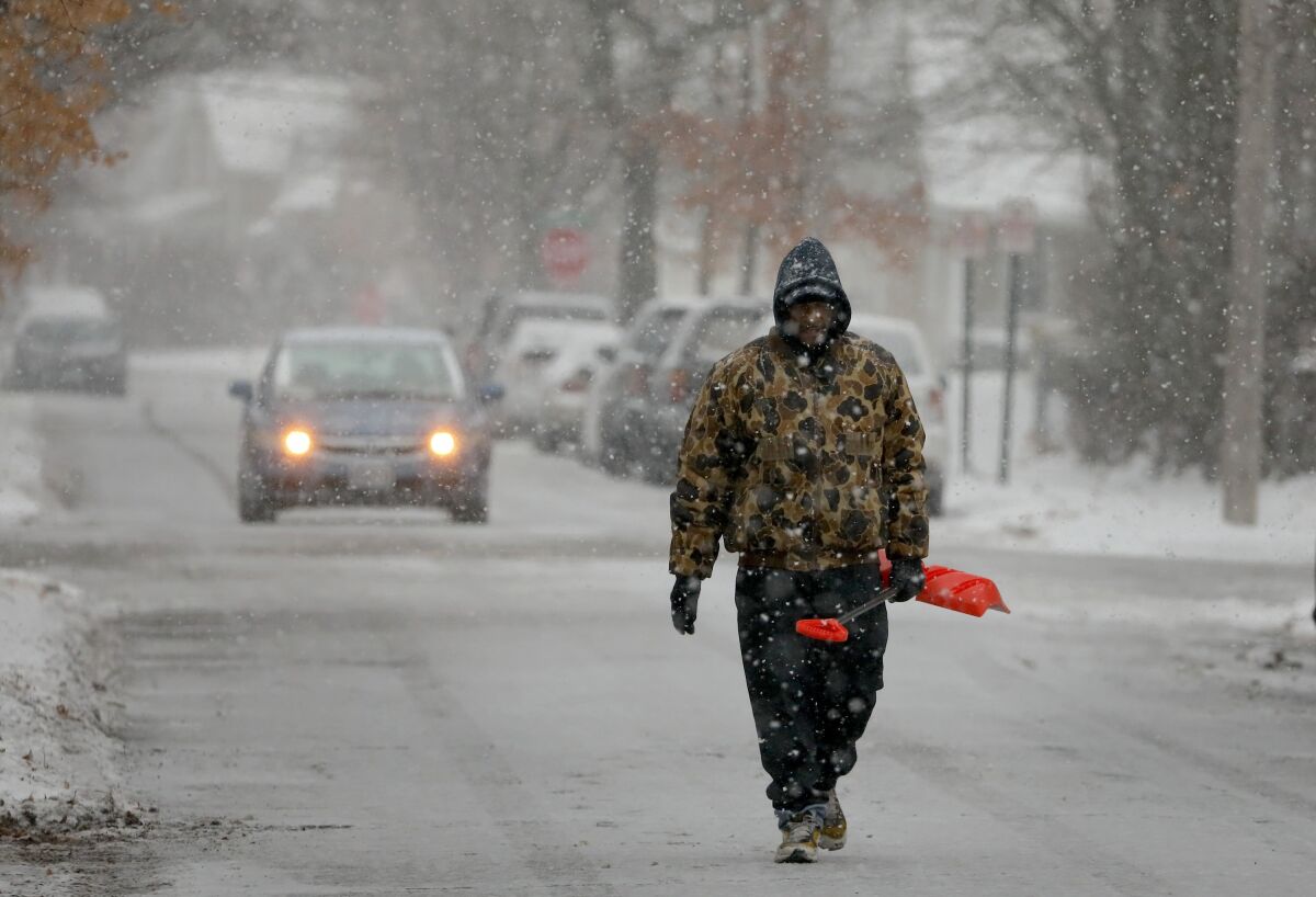 Bill Parham walks down an icy street in Maplewood, Mo., looking to clear snow off people's driveways and sidewalks on Monday. The wintry weather was part of a storm system that hit parts of the Midwest and was expected to extend into the Northeast through Tuesday, the National Weather Service said.