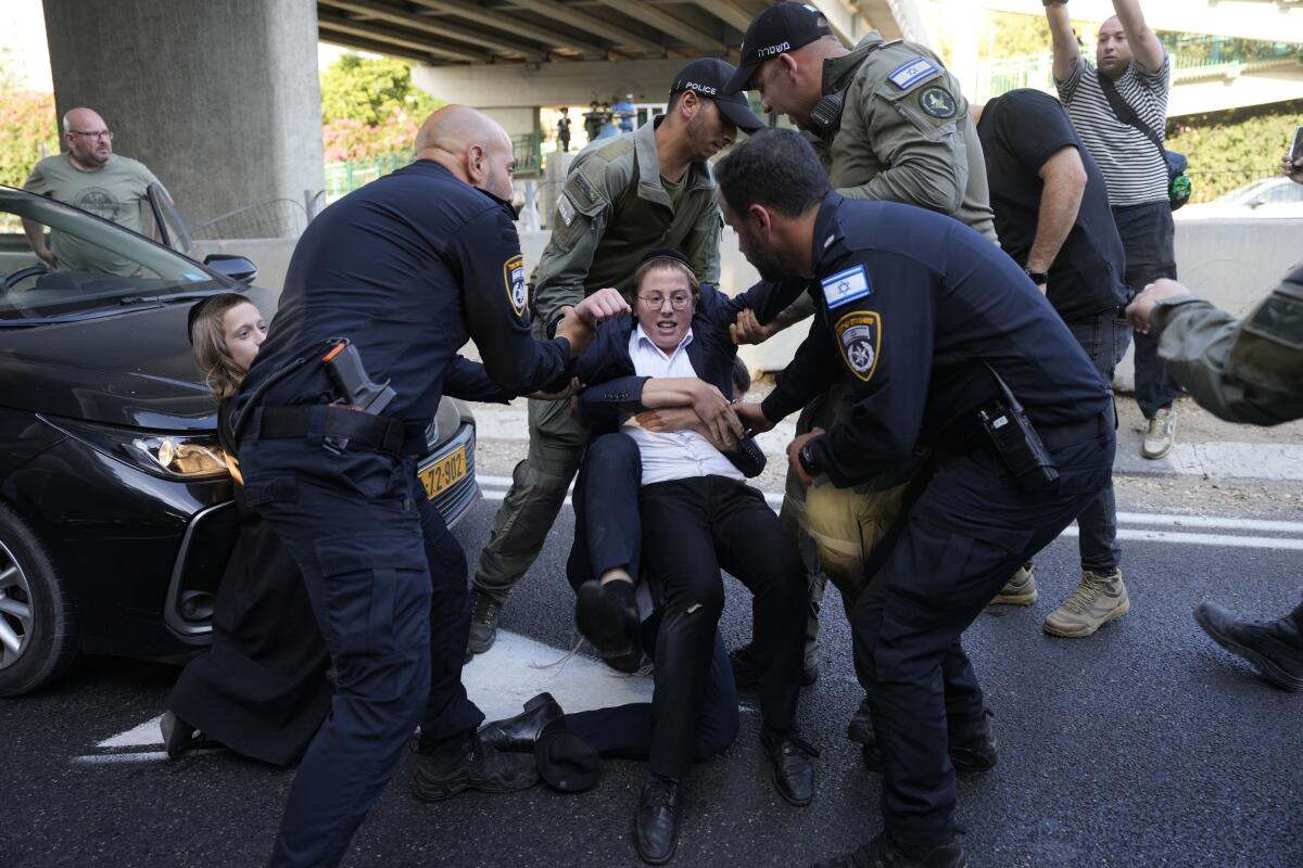 Israeli Police remove ultra-Orthodox Jewish youth blocking a road to protest military recruitment.