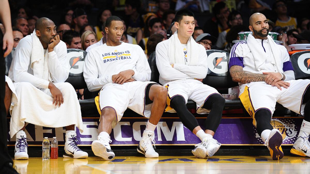 Lakers teammates (from left to right) Kobe Bryant, Wesley Johnson, Jeremy Lin and Carlos Boozer sit on the bench during the fourth quarter of a 136-115 loss to the Golden State Warriors at Staples Center on Sunday.