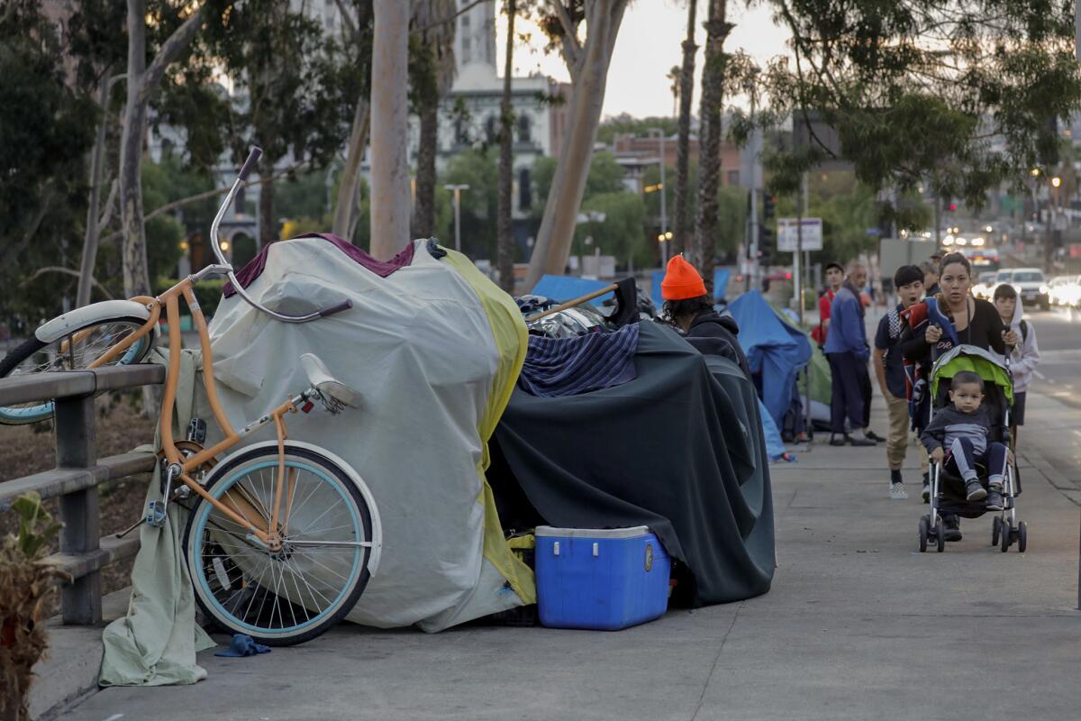 Pedestrians walk past tents along Arcadia Street in downtown Los Angeles in 2018.
