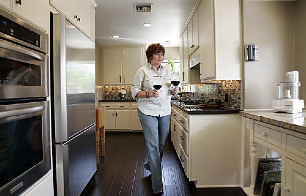 Vicki Reitz walks through the remodeled kitchen. By using the original kitchen's footprint and painting the cabinets, she completed the project for about $18,000.