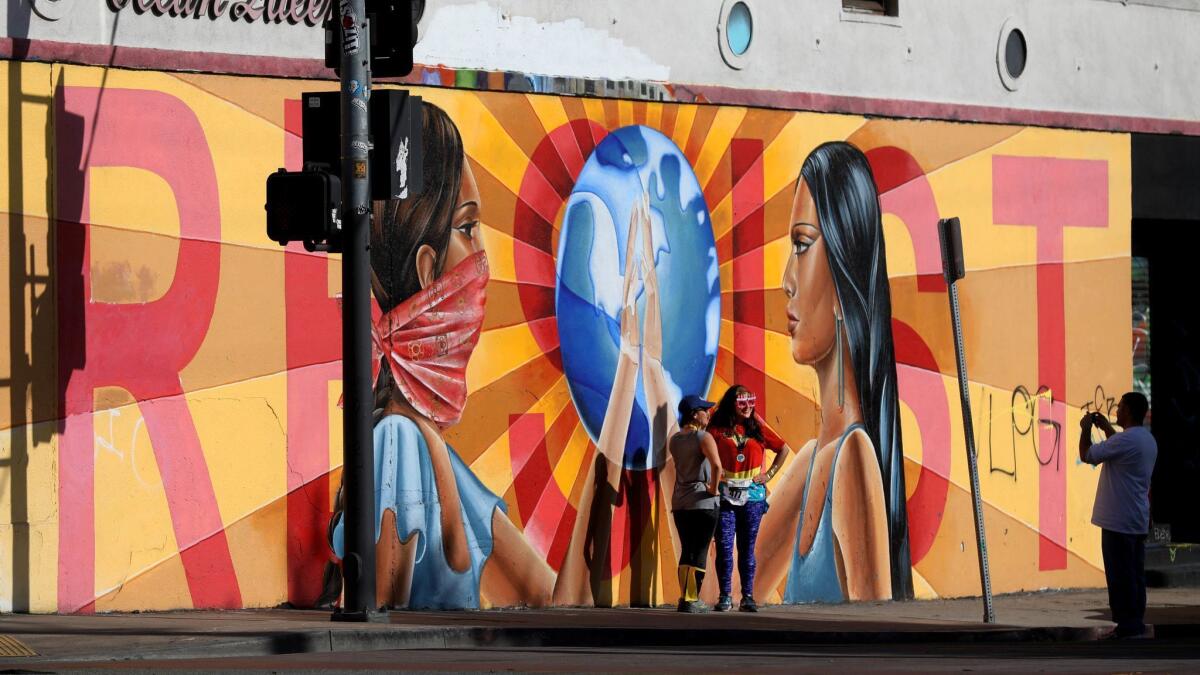 Women pose for a photograph before a Boyle Heights mural that reads "Resist" in April.