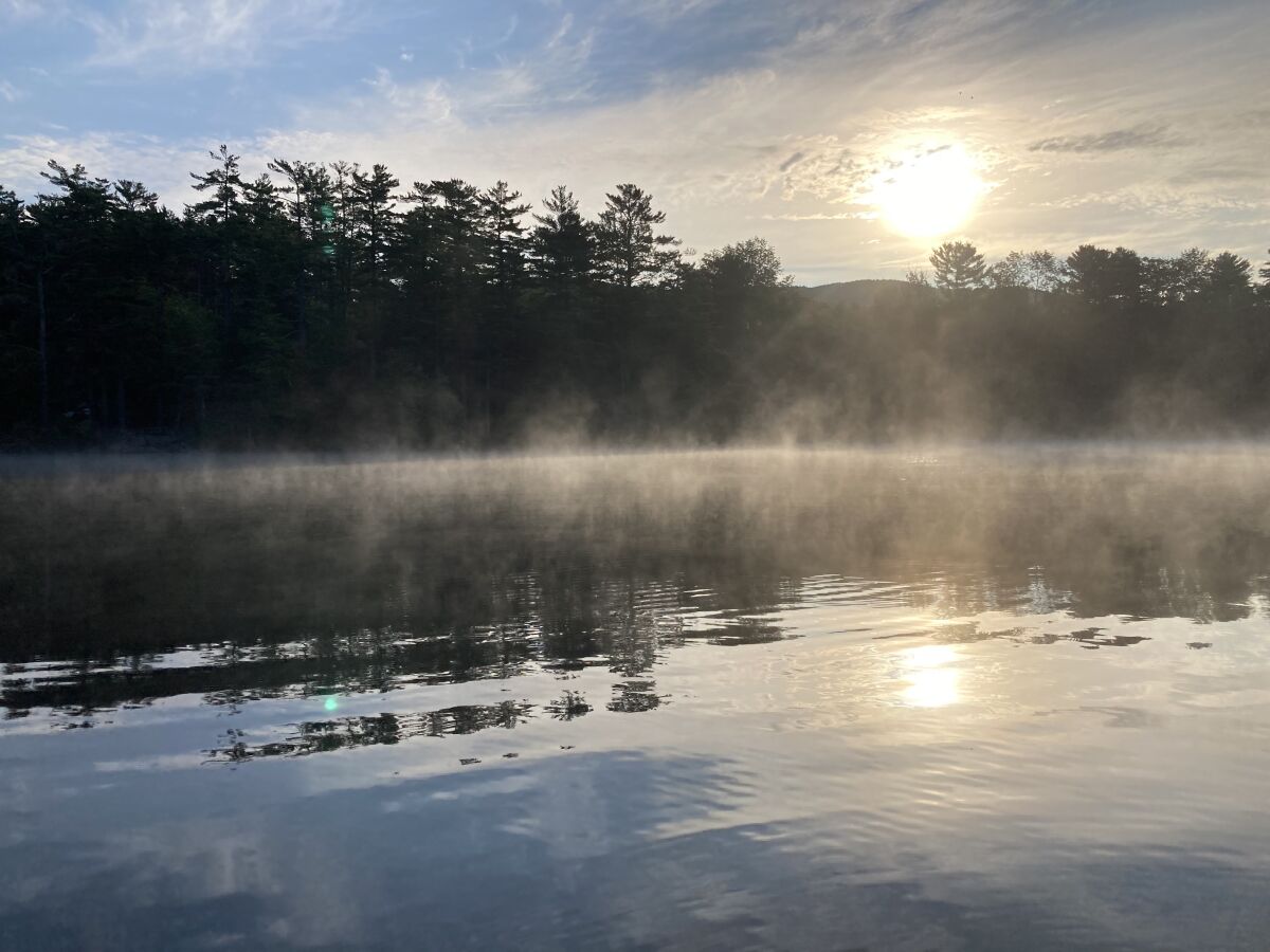 Mist rises off of Lake Megunticook, Maine.