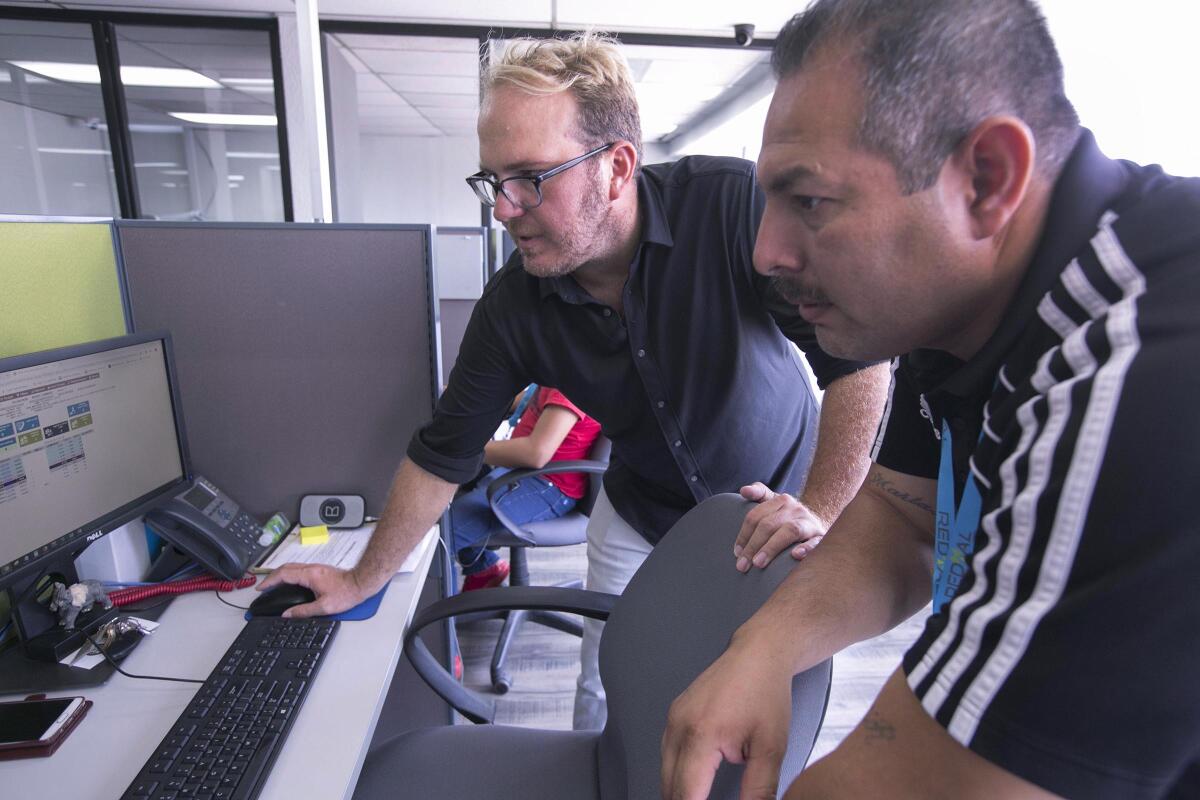 Jason Heil, left, cofounder of the Redial BPO call center in Tijuana, and supervisor Joaquin Aviles go over call volume Sept. 25.