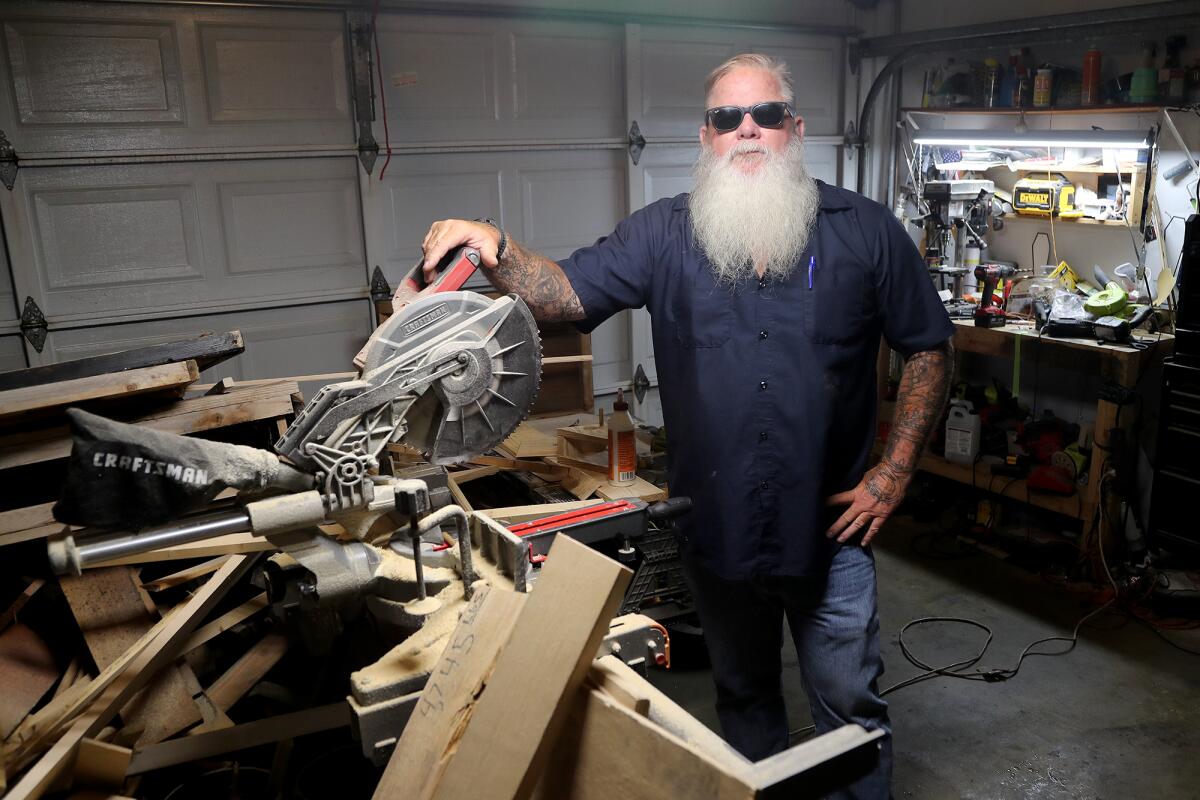 Jason Stout, 53, Friday stands at a work bench in the garage workshop of his Huntington Beach home.