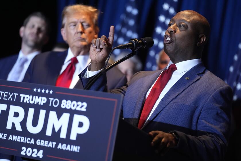 FILE - Republican presidential candidate former President Donald Trump listens as Sen. Tim Scott, R-S.C., speaks at a primary election night party at the South Carolina State Fairgrounds in Columbia, S.C., Saturday, Feb. 24, 2024. A top ally of former President Donald Trump — and a potential running mate — is launching a new effort to win over Black and other nonwhite working class voters he argues could be the deciding factor in November's elections. South Carolina Sen. Tim Scott, the only Black Republican in the Senate, will lead a $14 million campaign targeting minority voters in seven key swing states. (AP Photo/Andrew Harnik, File)