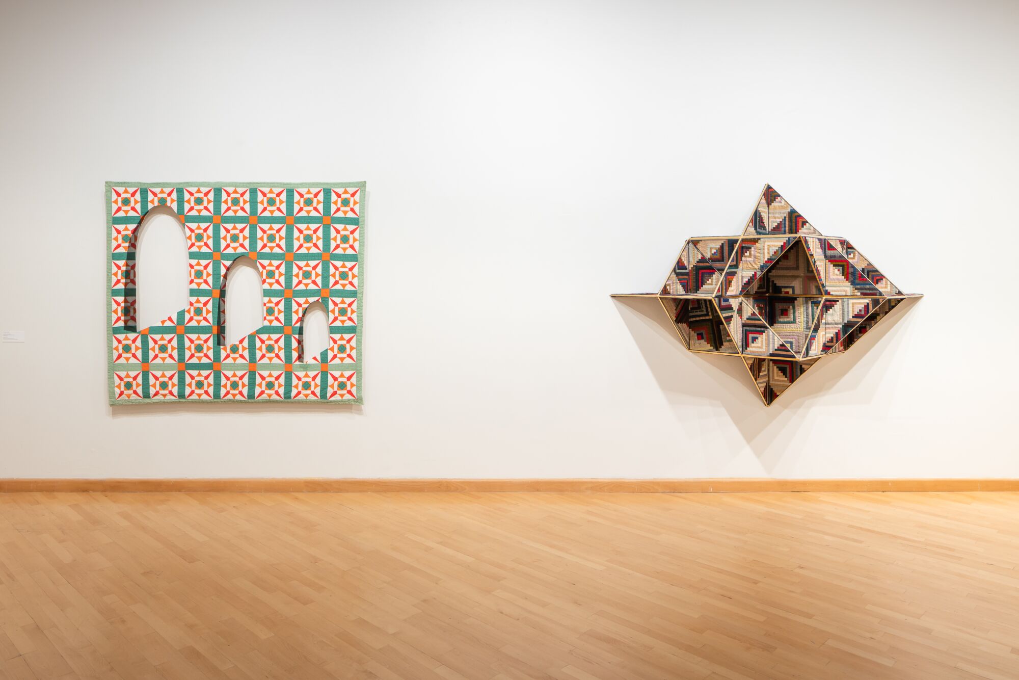A gallery shows works made with quilts: one features a series of arched cutouts, the other looks like a space ship