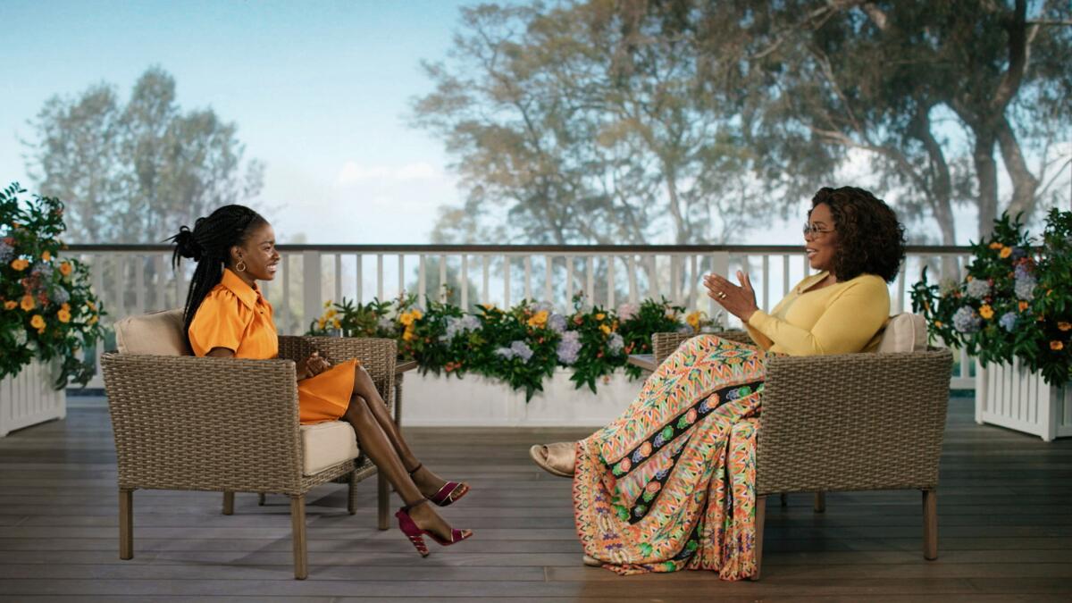 Amanda Gorman and Oprah Winfrey sitting across from each other in wicker chairs