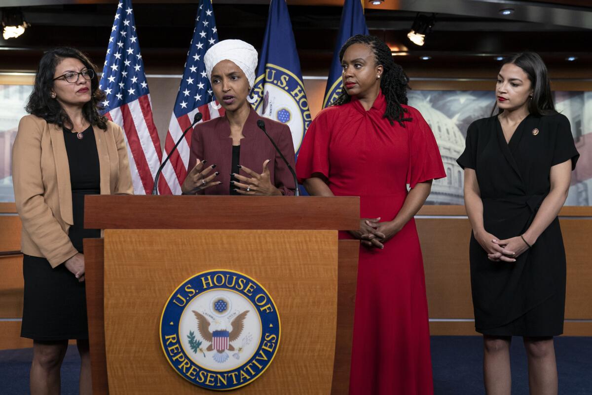 Four congresswomen stand at a lectern.