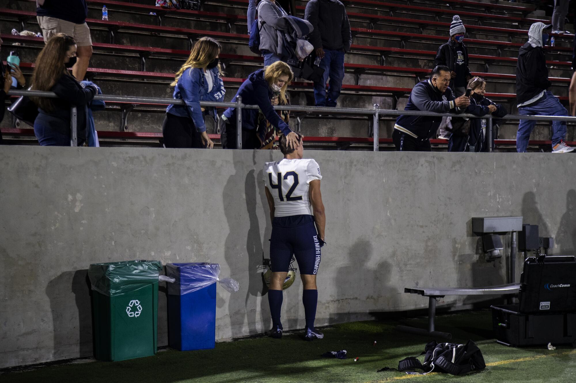 St. John Bosco senior linebacker Robby Vaughn stands beneath a woman in the stands who has her hand on his head..