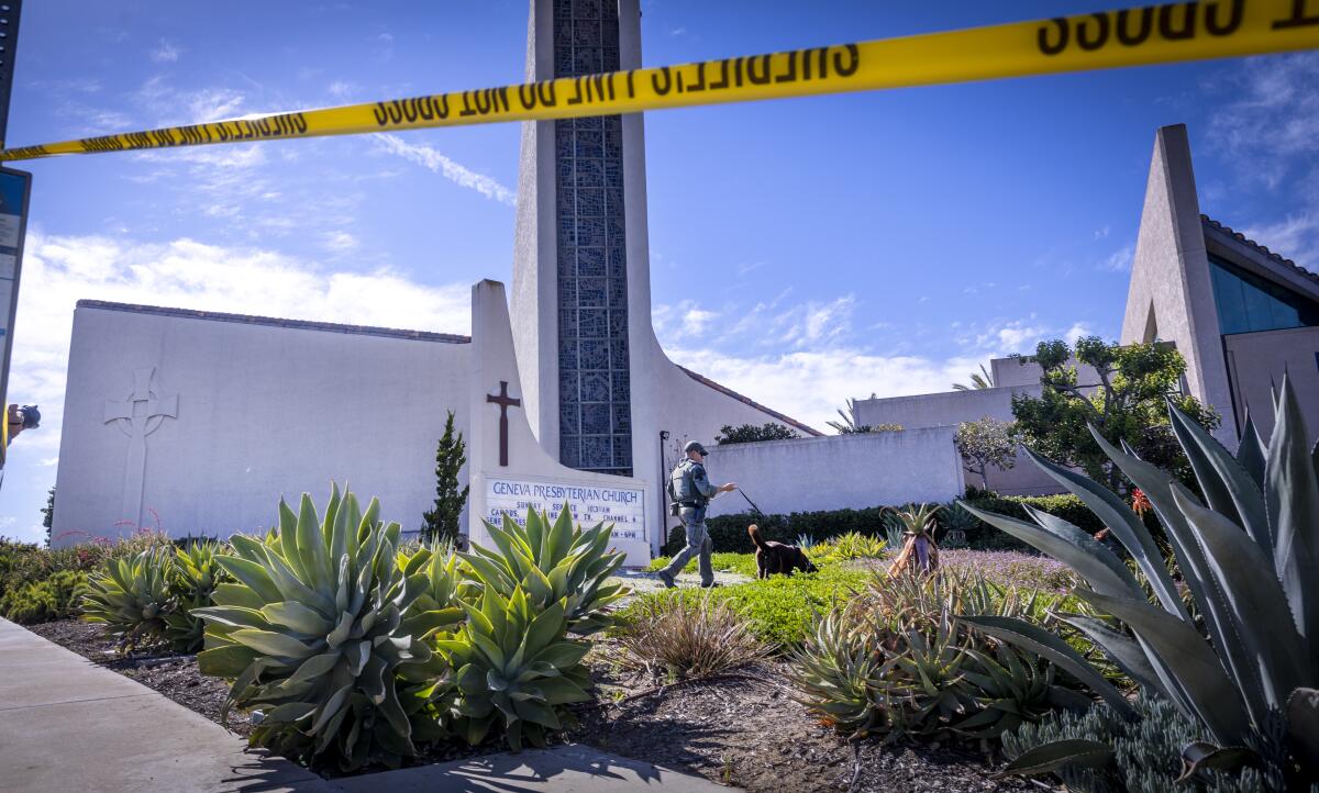 A law enforcement officer walks a K9 dog outside a church taped off 