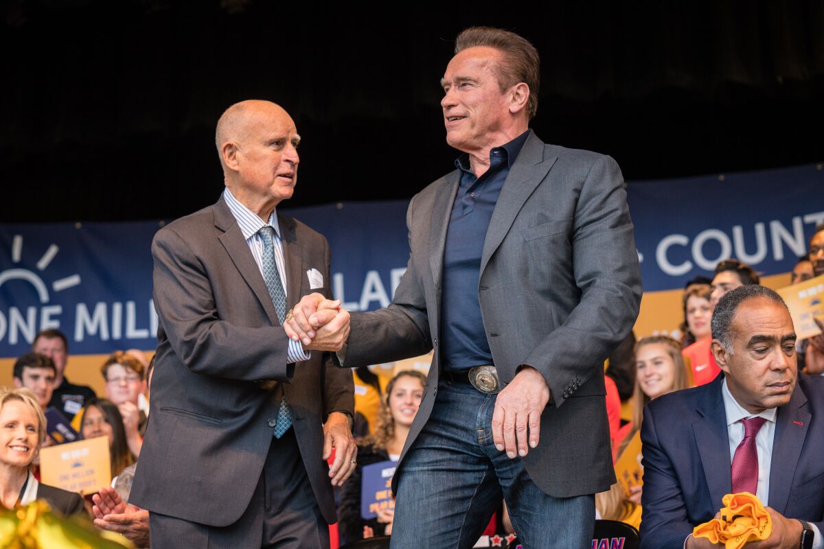 Former Governors Arnold Schwarzenegger and Jerry Brown grasp hands