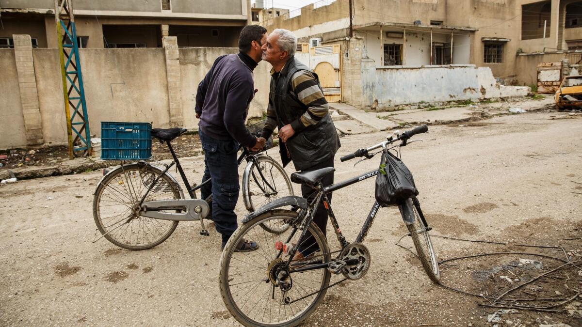 Mohammed Kamal Mahmoud greets a friend as he bikes around March 19 in Mosul, Iraq.