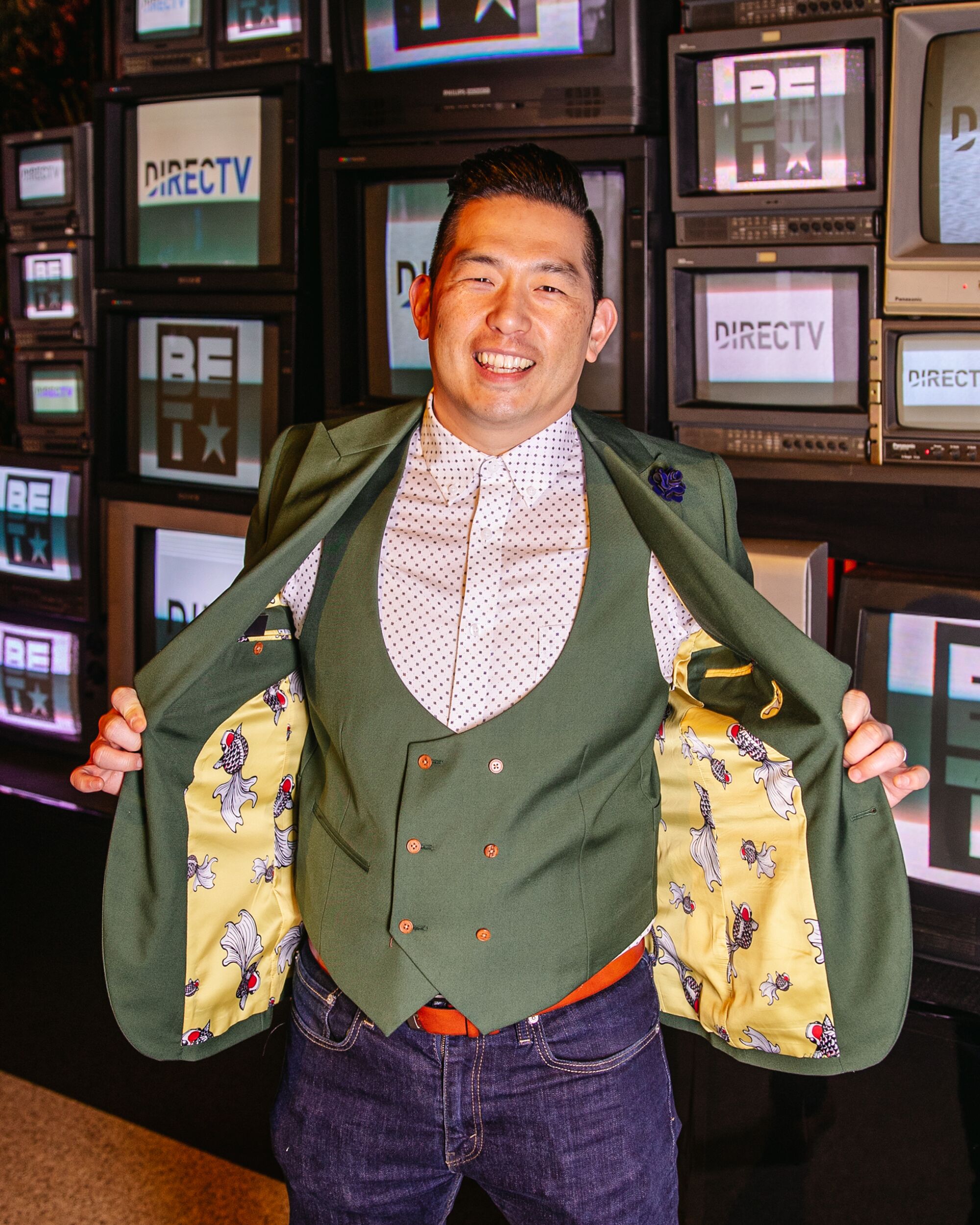 A man in a shirt, vest and jacket poses for a portrait.