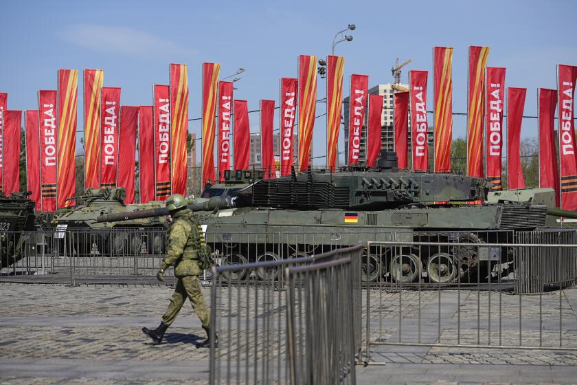 A Russian soldier walks past a Leopard 2A6 tank that belonged to the Ukrainian army is seen on display in Moscow. Tuesday, April 30, 2024. The Russian military put some of the equipment captured from Ukrainian forces on display in Moscow. (AP Photo/Alexander Zemlianichenko)