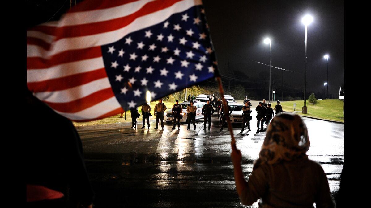 Police officers stand their ground as a protester waves the American flag along West Florissant Avenue during a demonstration in Ferguson, Mo., on Nov. 22.