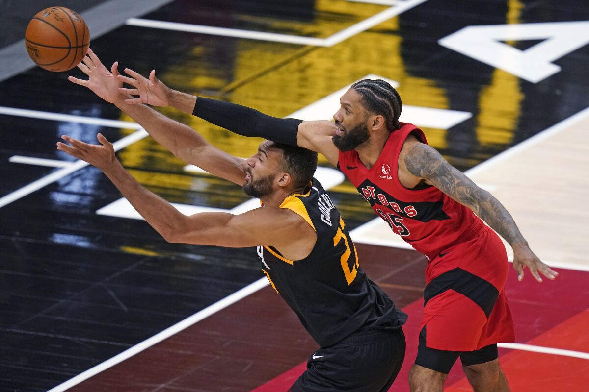 Toronto Raptors guard DeAndre' Bembry, right, and Utah Jazz center Rudy Gobert (27) reach for the ball during the second half of an NBA basketball game Saturday, May 1, 2021, in Salt Lake City. (AP Photo/Rick Bowmer)