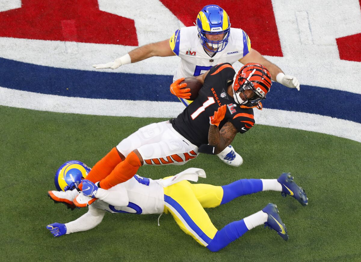 Bengals' Ja'Marr Chase is hit by Rams' Eric Weddle as Troy Reeder (51) moves in at Super Bowl LVI on Sunday at SoFi Stadium.