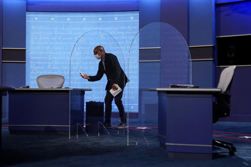 A worker stands onstage near protective plastic panels standing between tables for Vice President Mike Pence and Democratic vice presidential candidate, Sen. Kamala Harris, D-Calif., as preparations take place for the vice presidential debate in Kingsbury Hall at the University of Utah, Tuesday, Oct. 6, 2020, in Salt Lake City. (AP Photo/Patrick Semansky)