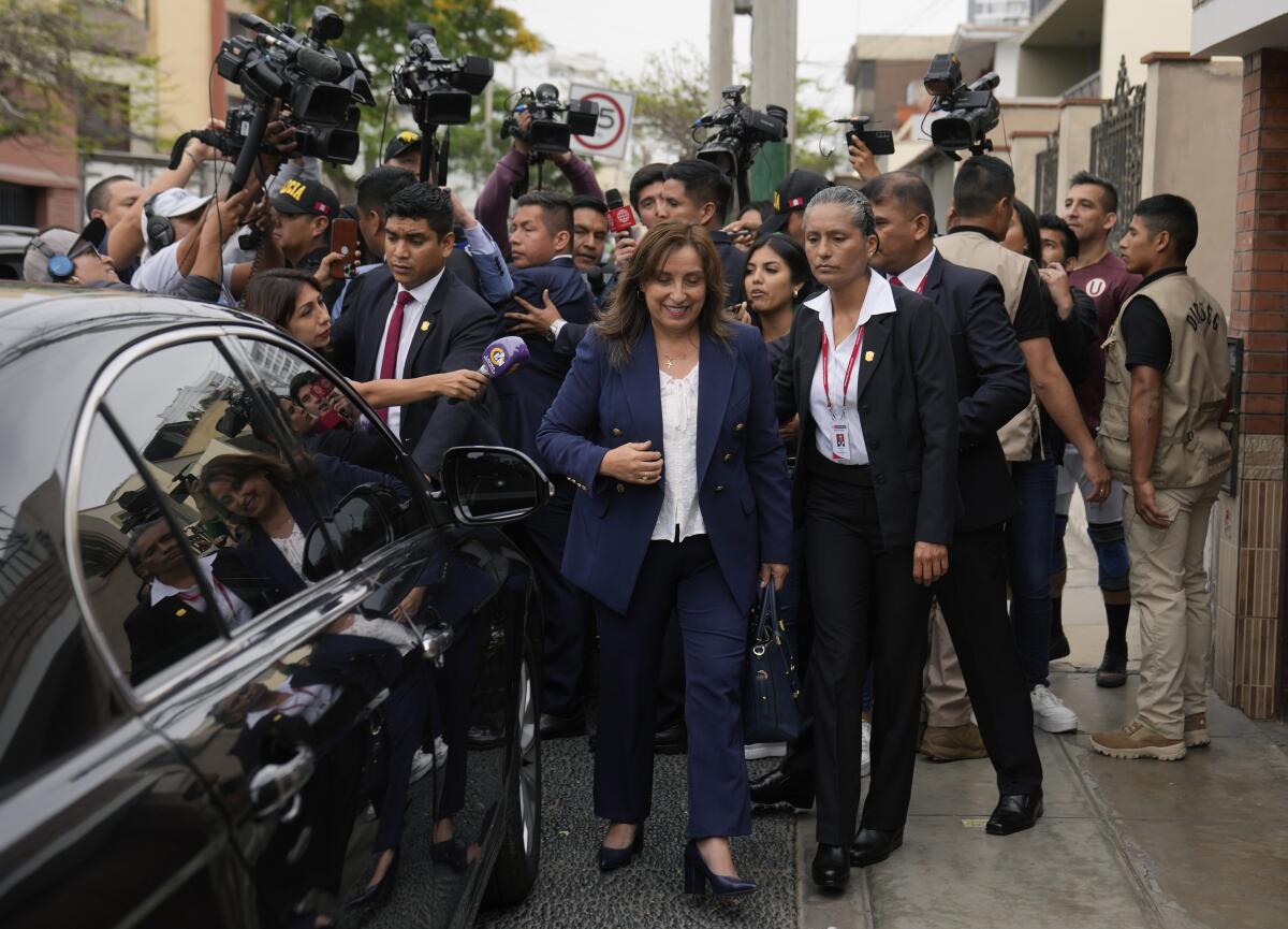 Peru's President Dina Boluarte walks to her car in front of a crowd.