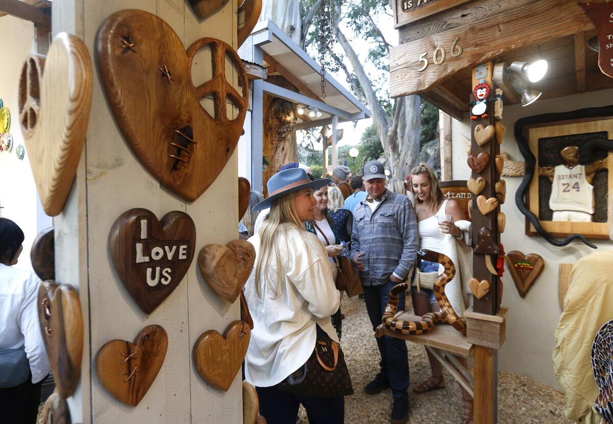 Guests gather around artist Shane Dunlap's booth of carved wooden creations at the Sawdust Art Festival on Tuesday.