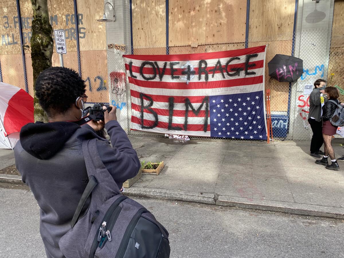 A man photographs an upside-down flag June 13 on a wall of the precinct that police deserted in Seattle's protest zone.