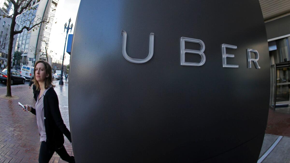 In this file photo taken Dec. 16, 2014, a woman walks past the company logo of the Internet car service, Uber, in San Francisco.