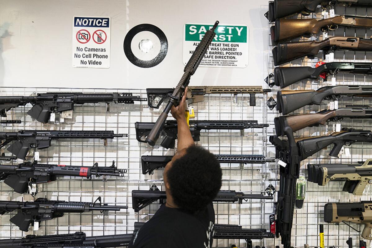 A sales associate grabs an AR-15-style rifle to show to a customer at Burbank Ammo & Guns.