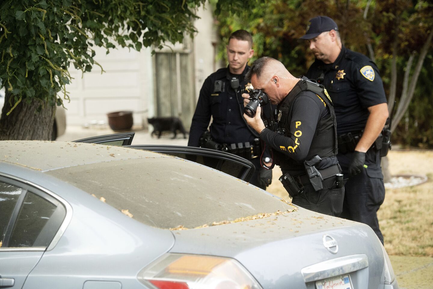 A police officer photographs a car outside the home linked to the suspected Gilroy Garlic Festival gunman.