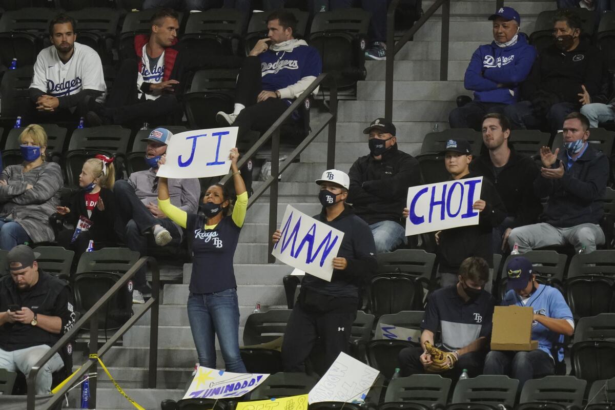 In the stands, fans of Ji-Man Choi hold signs with the Tampa Bay Rays first baseman's name.