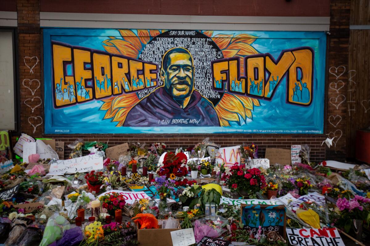 Flowers surround a Minneapolis mural honoring George Floyd.