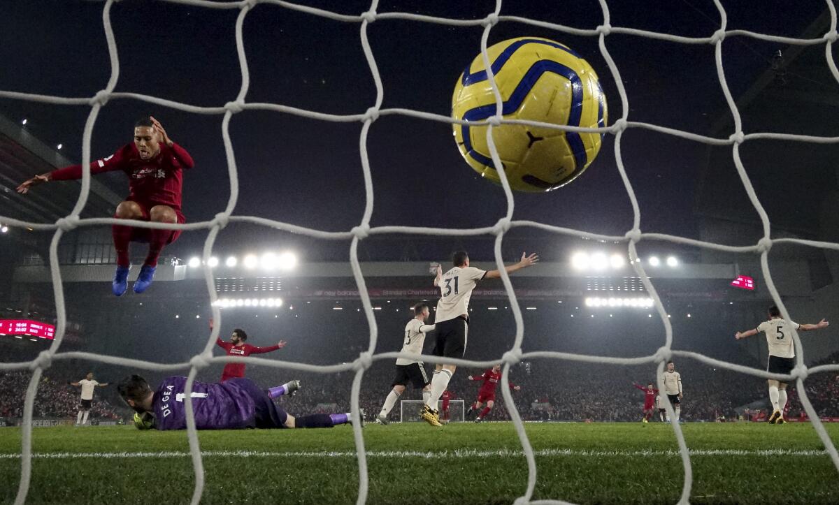 Liverpool's Virgil van Dijk, left, jumps over Manchester United's goalkeeper David de Gea after a disallowed goal during the English Premier League soccer match between Liverpool and Manchester United at Anfield Stadium in Liverpool, Sunday, Jan. 19, 2020.(AP Photo/Jon Super)
