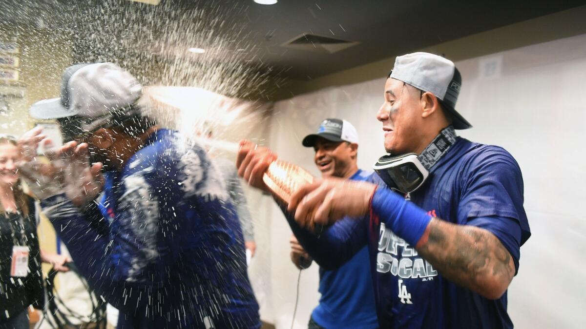The Dodgers' Manny Machado, right, sprays teammate Matt Kemp after the team clinched a playoff berth on Saturday.