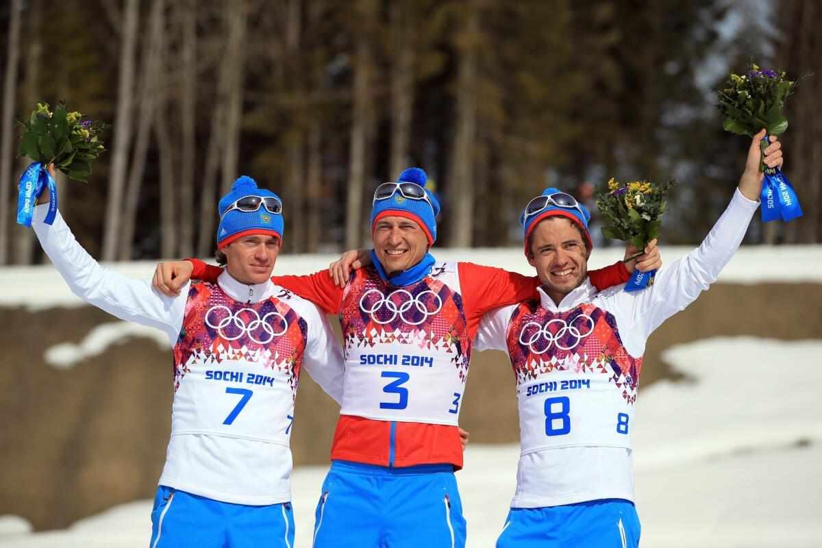 Gold medalist Alexander Legkov (3) is flanked team silver medalist Maxim Vylegzhanin (7) and bronze medalist Ilia Chernousov (8) as they celebrate a Russian sweep of the men's cross-country 50-kilometer mass start race Sunday at the Sochi Olympics.