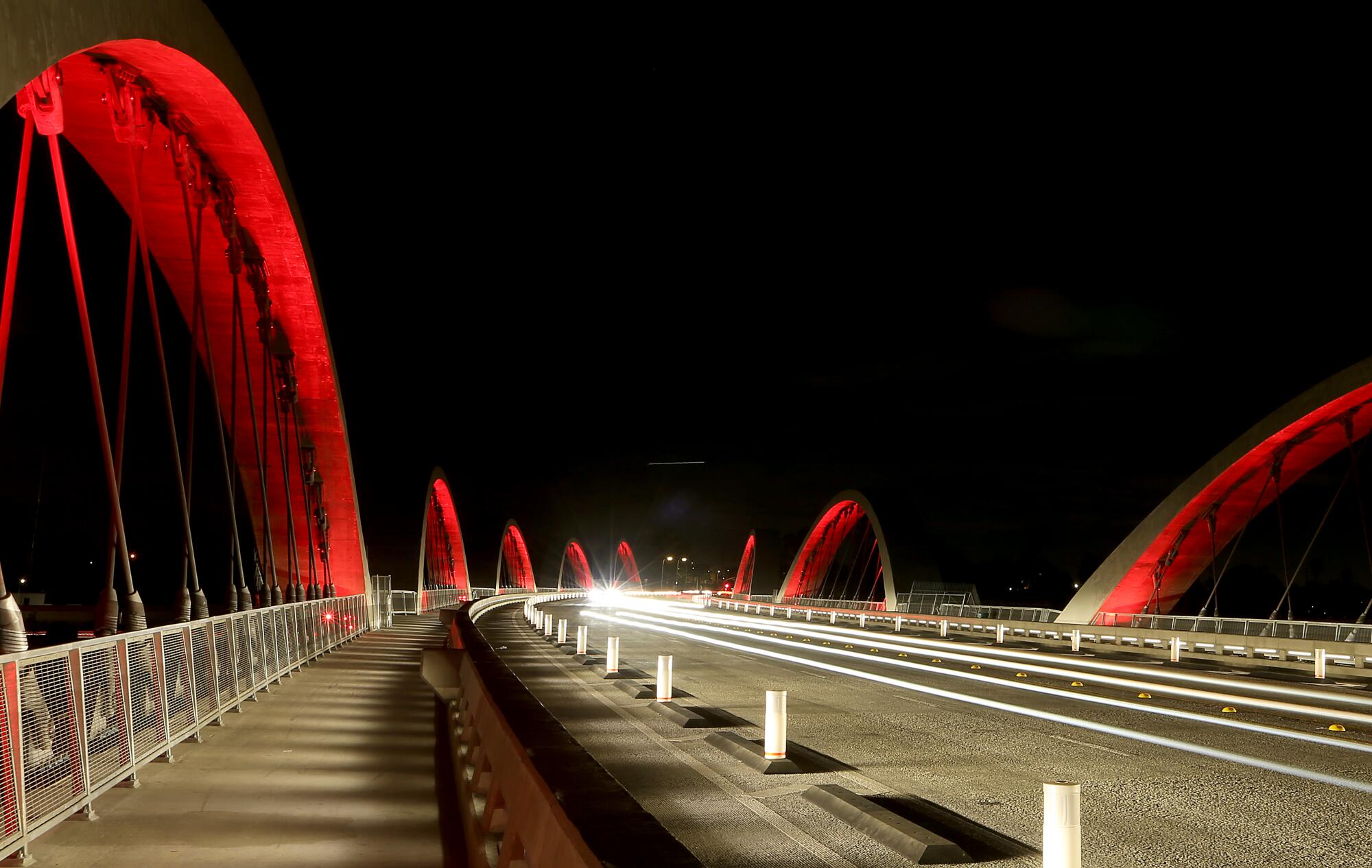 Arches on a bridge are lighted red.