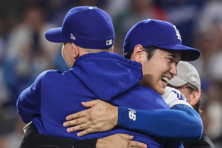 Dodgers designated hitter Shohei Ohtani hugs teammate Walker Buehler as they celebrate clinching a division title