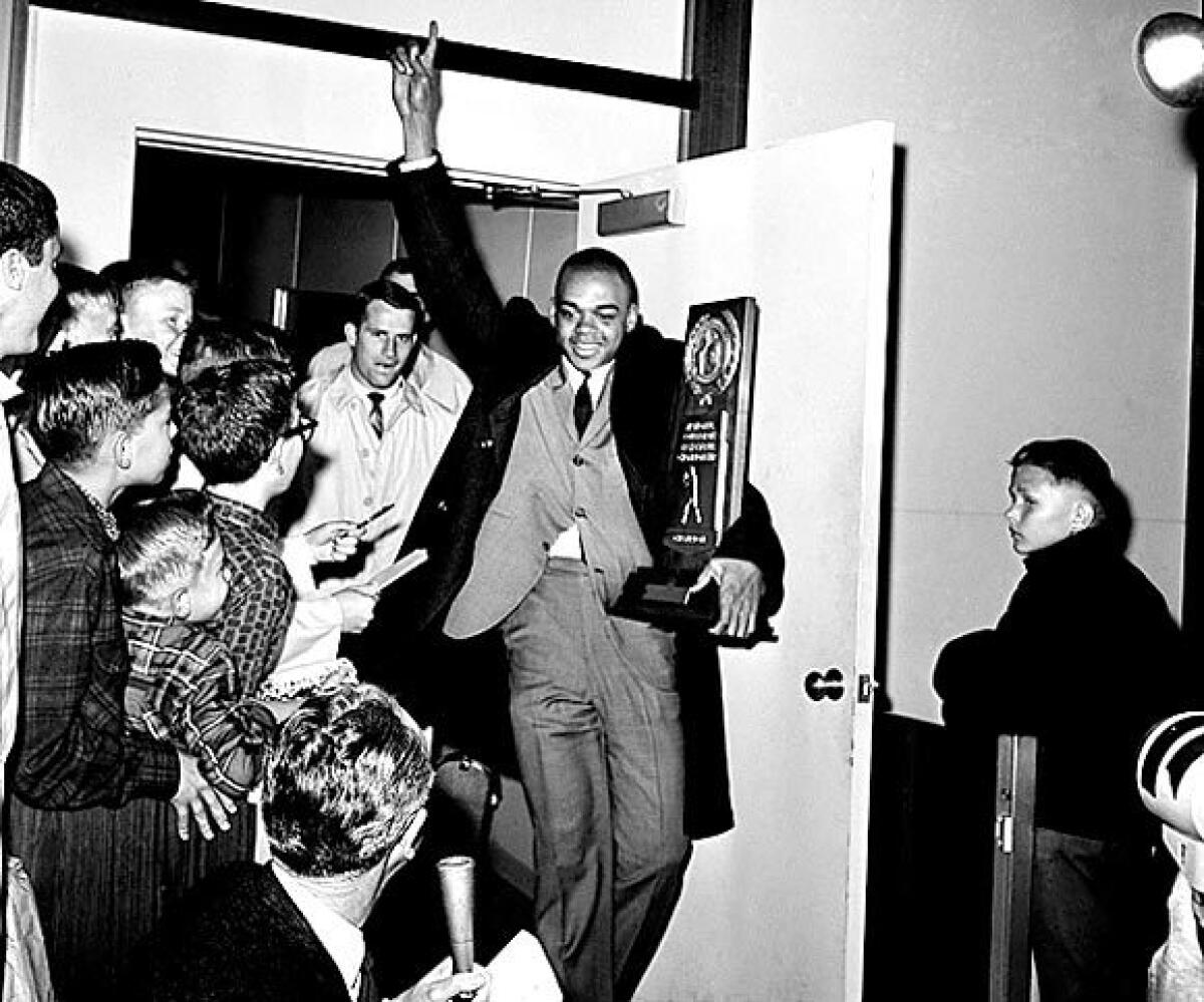 UCLA's Walt Hazzard, carries the NCAA's basketball championship trophy as the Bruins arrive in Los Angeles. More than 1,800 fans were on hand for the welcome in 1964.
